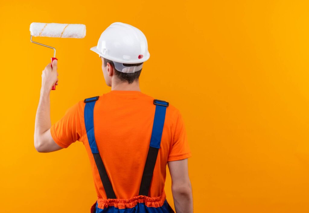 Hombre pintando pared color naranja